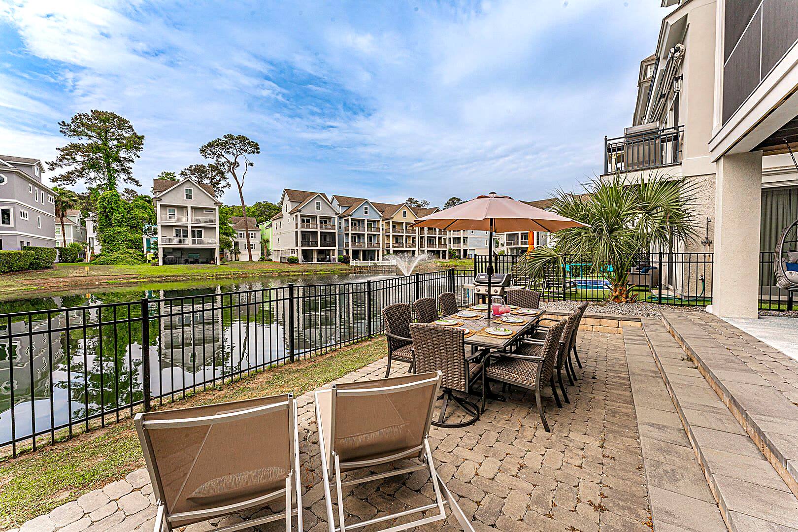 Outdoor dining table for eight on the paver patio at 122 Sandcastle Court overlooking the lagoon and fountain
