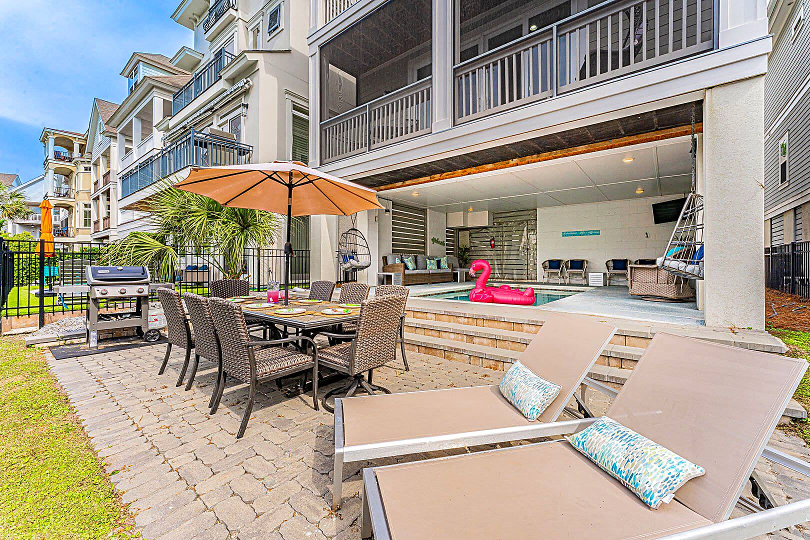 Pool, paver patio, gas grill and outdoor dining table at 122 Sandcastle Court seen from the lagoon lawn